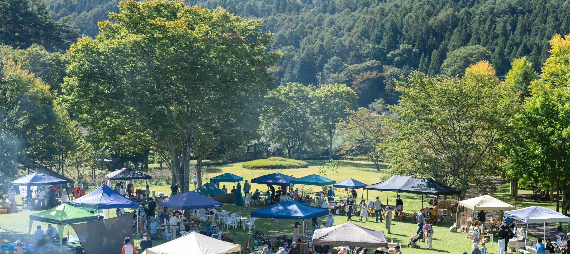 高台から見た森のマルシェの会場。山を背に色とりどりのテントが並び、大勢の人が歩いている