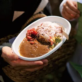 楕円の紙皿に、ご飯と鹿カレーが盛られ、手で持って渡されている。