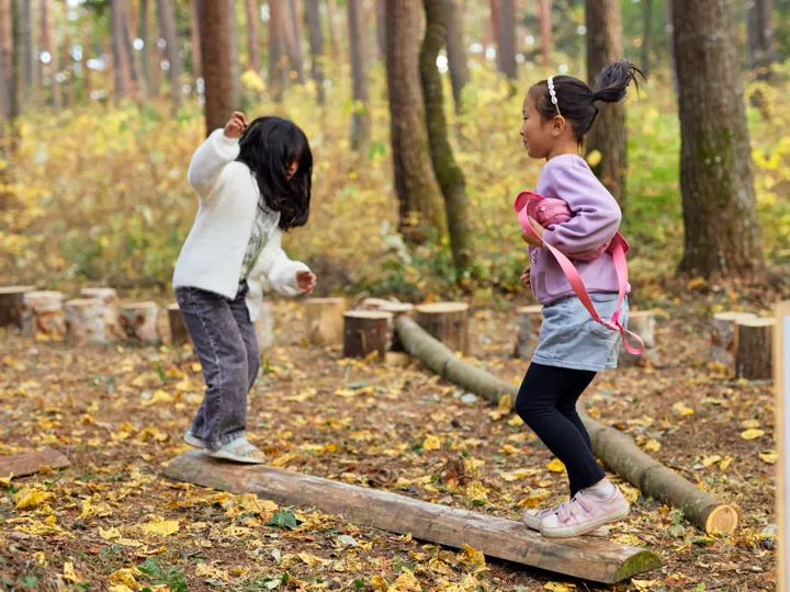 白いニット帽の女の子が、串に刺したおやつを口にくわえて、声を出して笑っている。